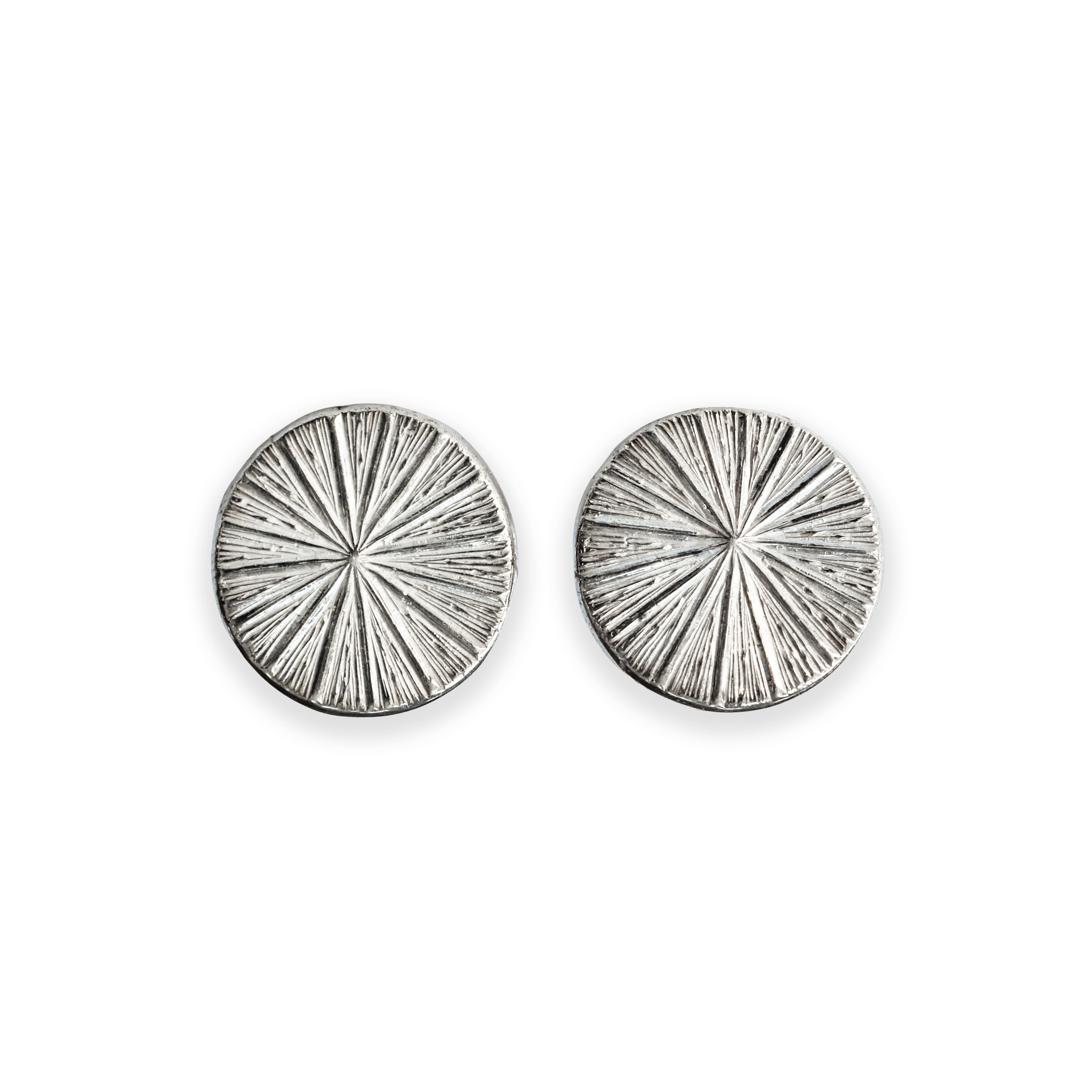 Pair of silver circular earrings with radiating design on a white background