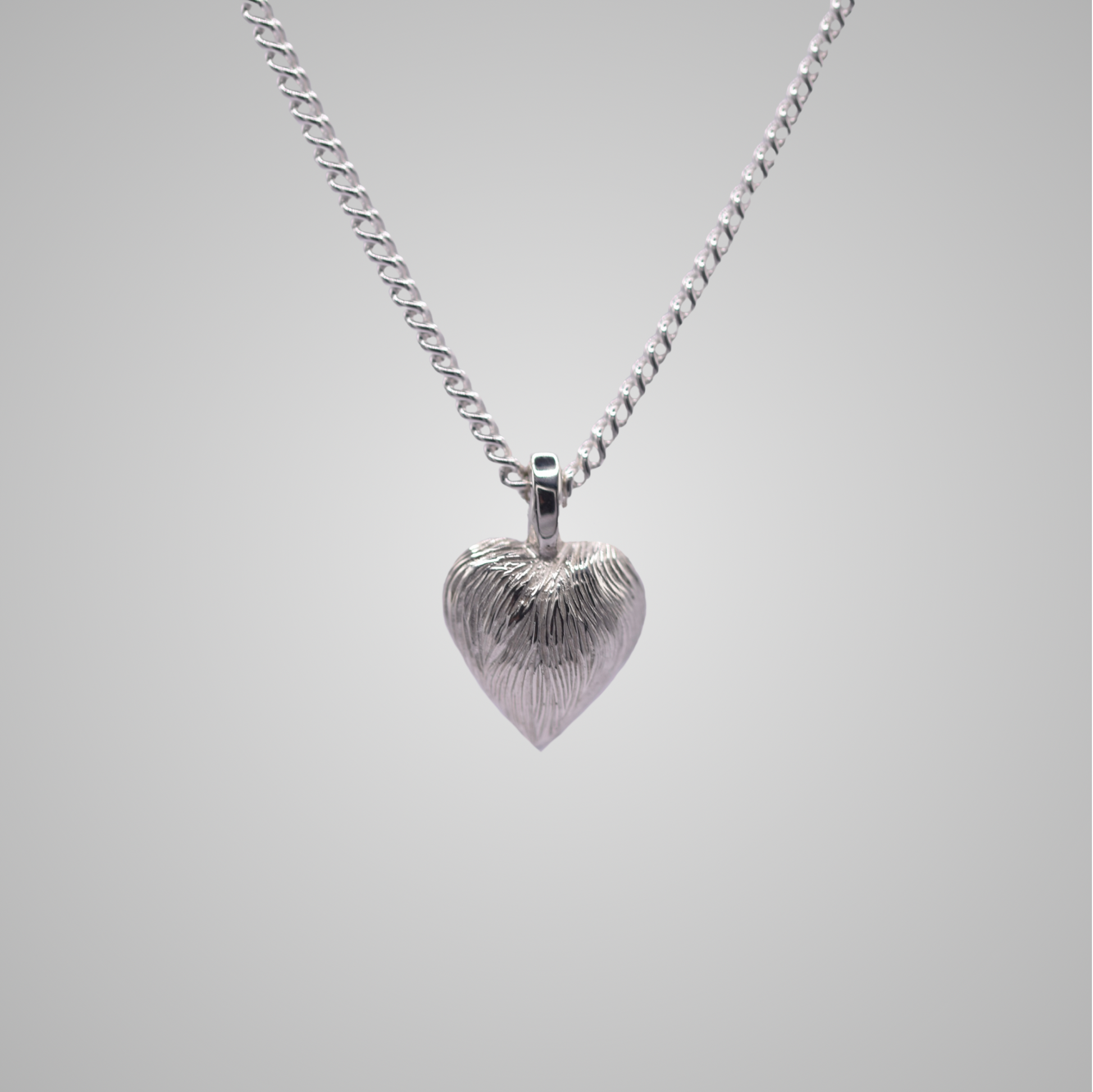 Silver heart pendant on silver chain with shiny engraved flowing lines 
