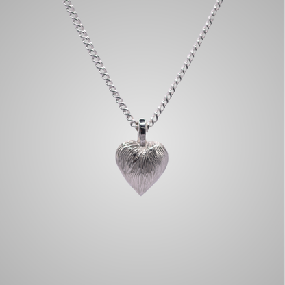 Silver heart pendant on silver chain with shiny engraved flowing lines 