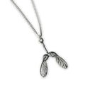 Silver necklace with a sycamore seed pendant on a white background