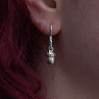Girl with red hair is wearing a silver earring that is a detailed acorn 