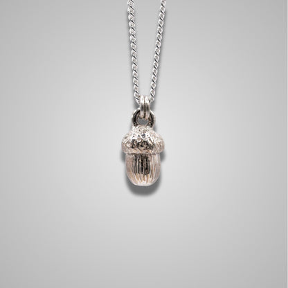 Sterling silver acorn pendant hangs from a silver chain. Intricate and shiny handmade jewellery. 