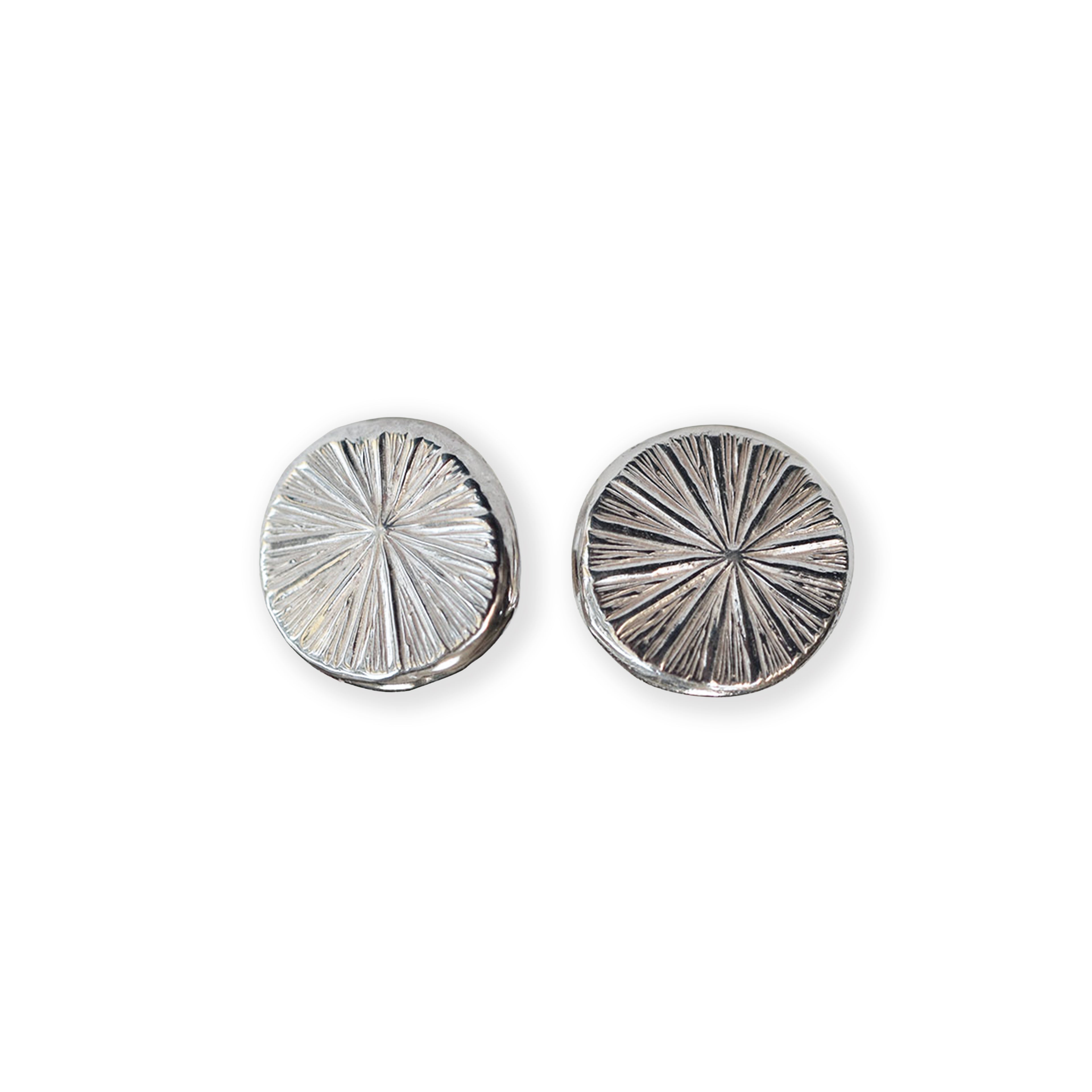 Pair of silver circular earrings with radiating texture on a white background
