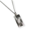 Silver necklace with a textured hand engraved wave patterned pendant on a white background