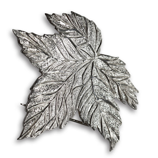 Silver leaf-shaped brooch on a white background