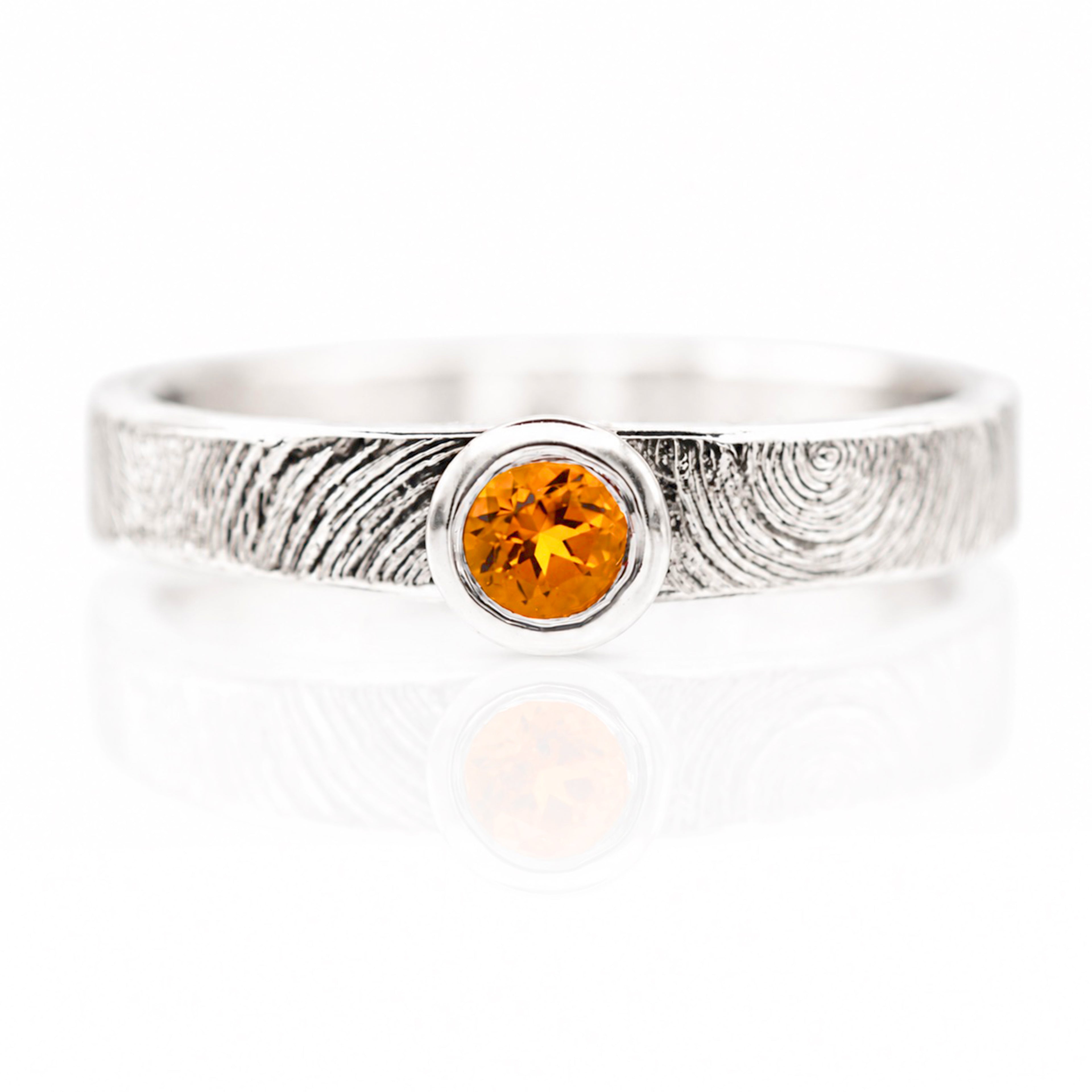 Silver ring with a central orange gemstone on a white background
