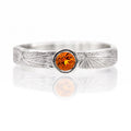 Silver ring with a round orange gemstone on a white background