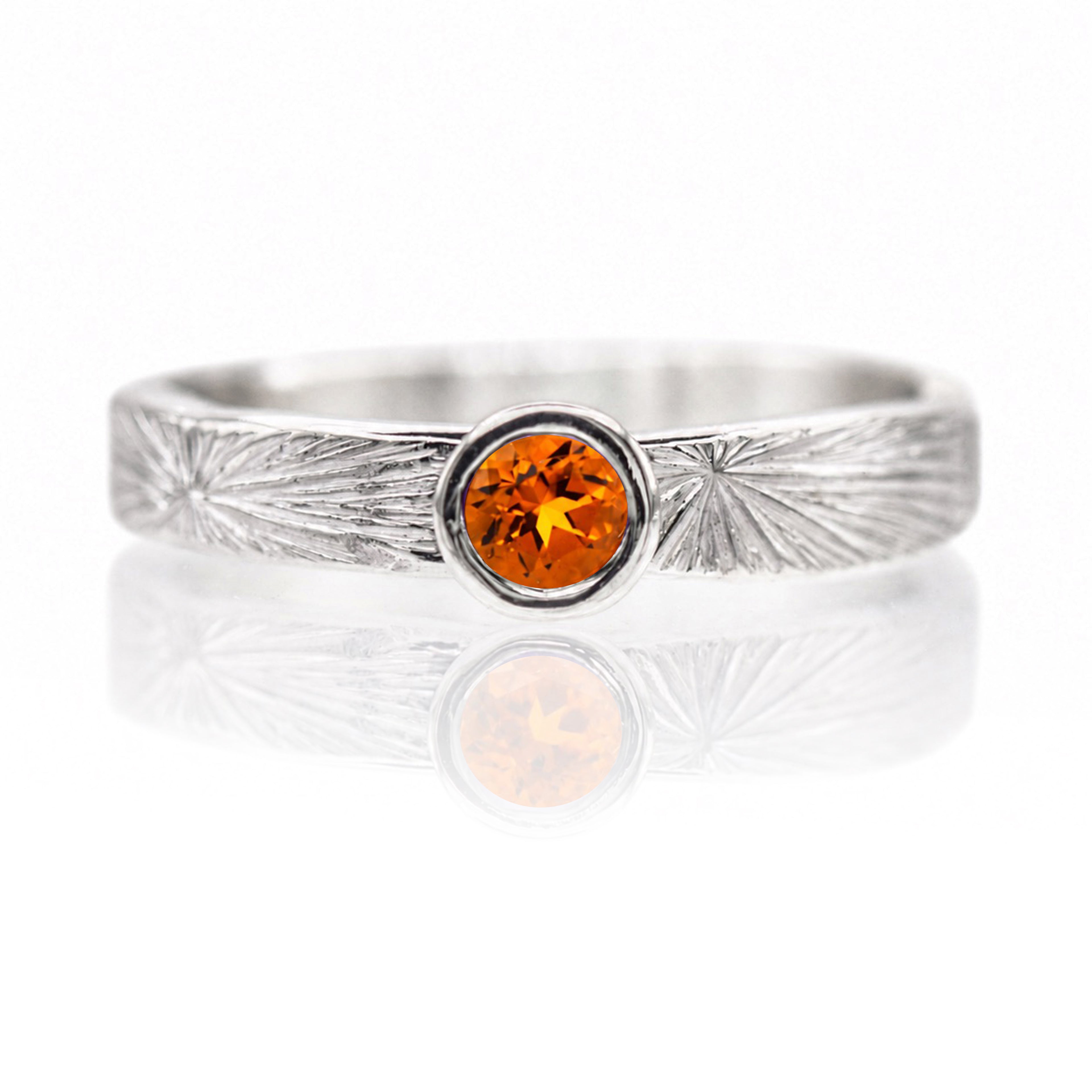Silver ring with a round orange gemstone on a white background